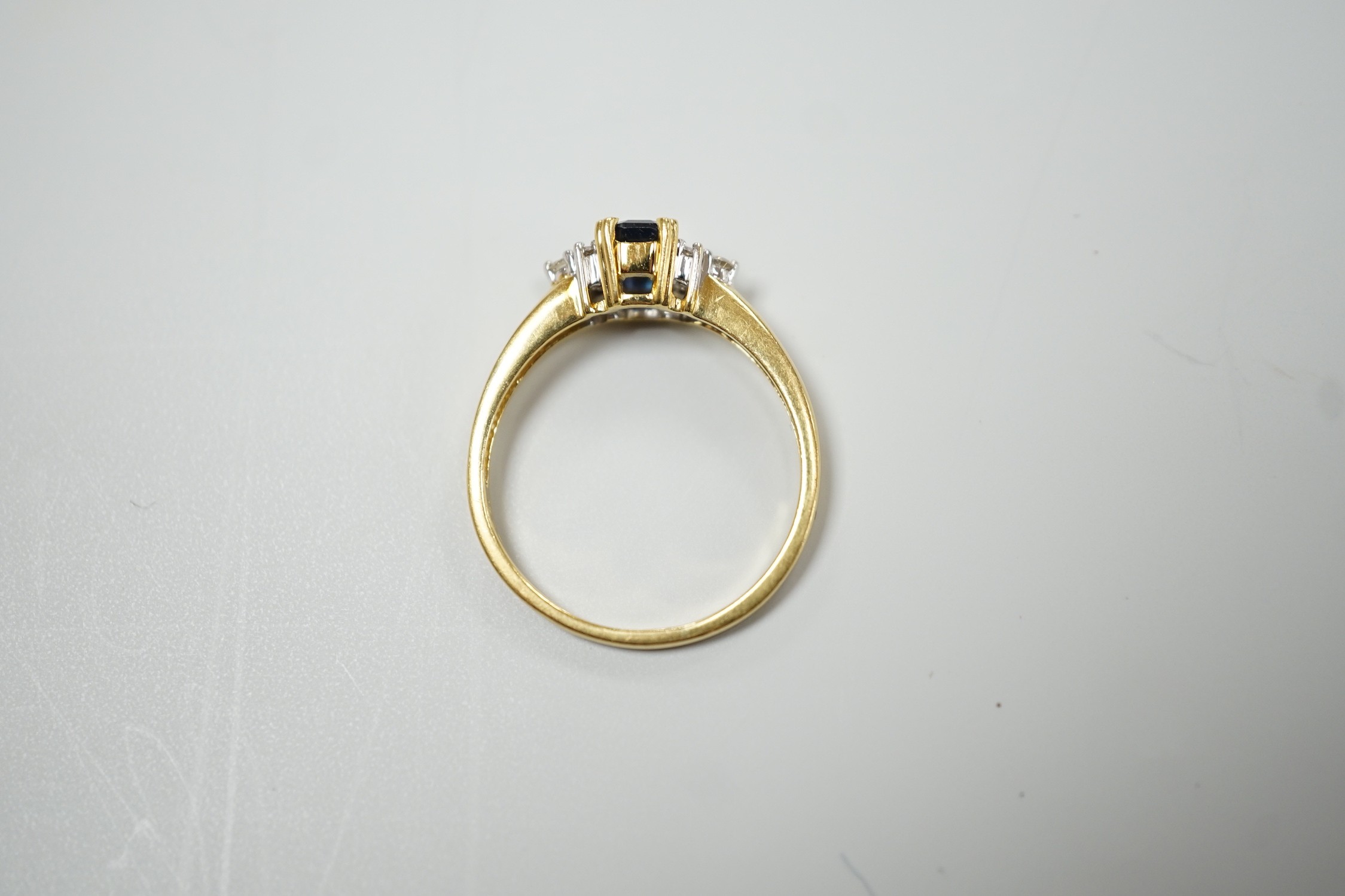 A modern 18ct gold and single stone sapphire set ring, with six stone diamond set shoulders, size R, gross weight 3.2 grams.